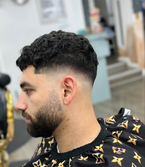 Textured haircut with a precise skin fade and shaped beard at The Room Barber