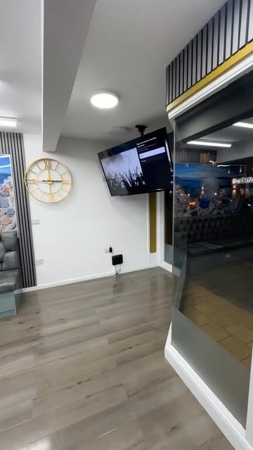 Inside The Room Barber, with pale walls, black and gold detailing and wood-effect flooring